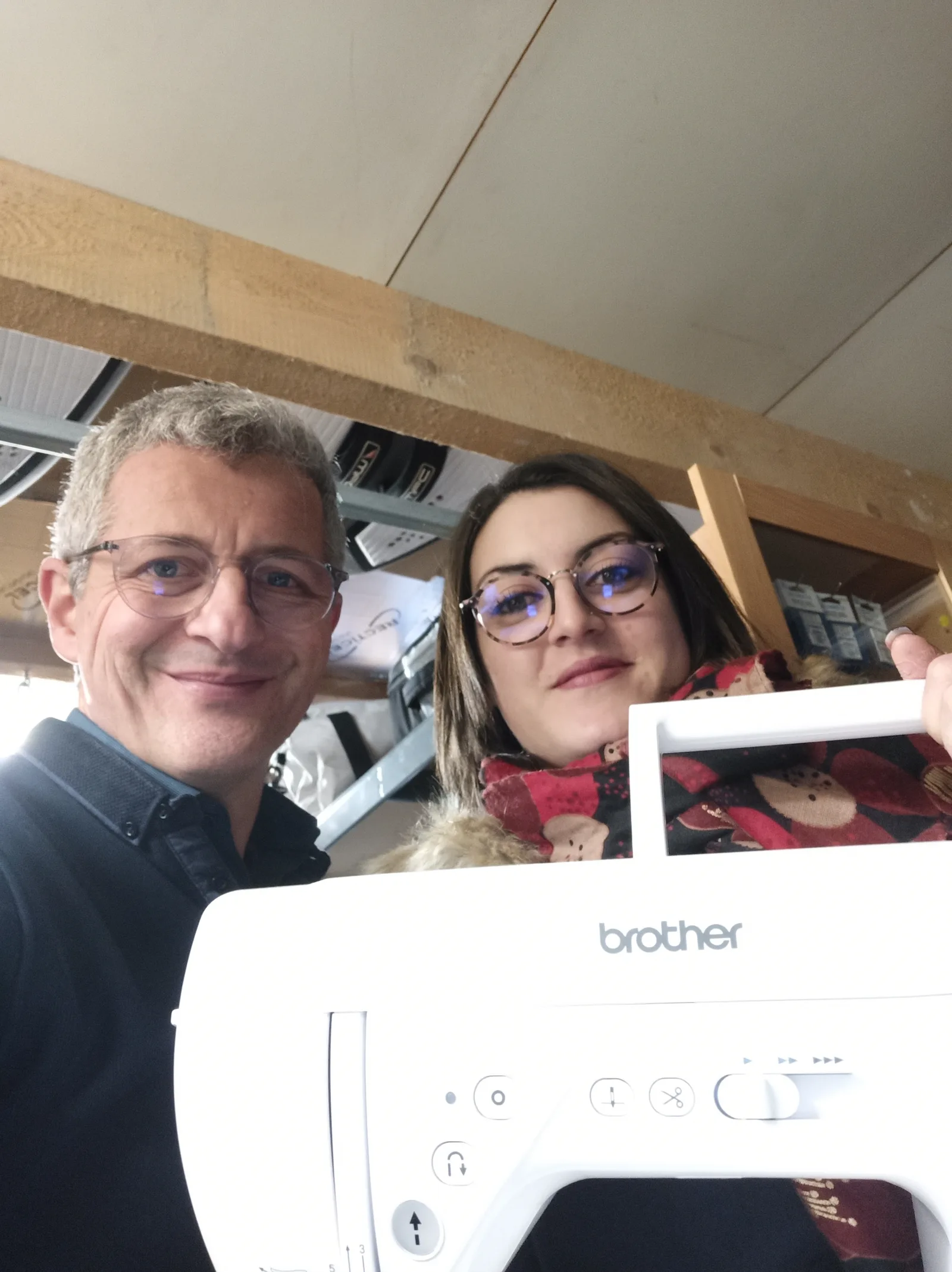 Une cliente repart avec sa nouvelle machine à coudre, accueillie par l'atelier.